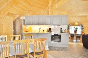 a kitchen with white cabinets and a table with chairs at Cape Marina Lodge in Skarsvåg