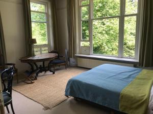 a bedroom with a bed and a table and windows at De Jufferen Lunsingh in Westervelde