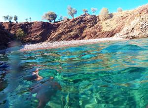 a person swimming in the water near a hill at Casa Doria in Léntas