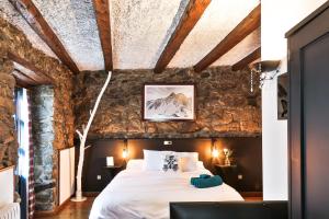 una camera con un grande letto in una parete in pietra di Hostal Cisco de Sans ad Andorra la Vella