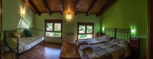 a bedroom with green walls and two beds and a table at Casa Rural El Serrano in Prioro