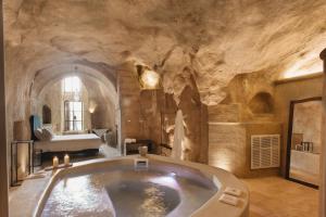 a large bathroom with a bath tub in a stone wall at Palazzo Del Duca Hotel & Restaurant in Matera +65 photos