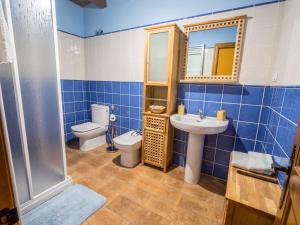 a blue tiled bathroom with a toilet and a sink at Casa Rural El Serrano in Prioro +27 photos