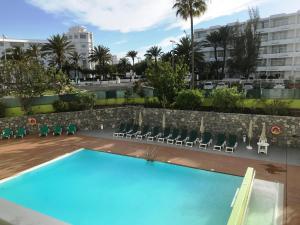 vistas a una piscina con sillas y a un edificio en Apartamentos Los Aguacates, en Playa del Inglés