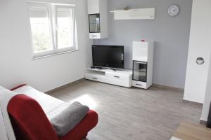 een woonkamer met een tv en een rode stoel bij Apartmani Neja in Bibinje