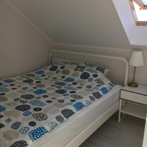 a bed with a blue and white quilt on it at Apartamenty Baltyk in Karwia