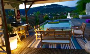 a deck with a pool with chairs and a table at B&B Les Hauts d'Ornans in Ornans