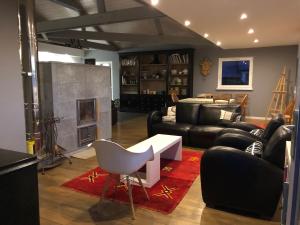 a living room with black leather furniture and a fireplace at B&B Les Hauts d'Ornans in Ornans