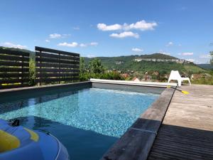 a swimming pool with a white chair sitting on a deck at B&B Les Hauts d'Ornans in Ornans