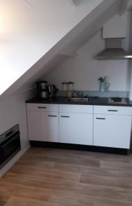 a kitchen with white cabinets and a stove at By The Sea in Vlissingen
