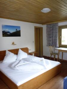 a bedroom with a large white bed with a wooden ceiling at Sportpension Penhab in Saalbach Hinterglemm