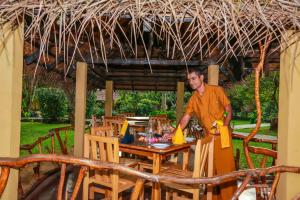 un homme se tient devant une table dans l'établissement Pelwehera Village Resort, à Dambulla