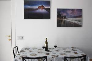 a table with a bottle of wine and two paintings at Apartamento de playa reformado in Rincón de la Victoria