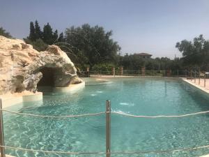 a swimming pool with a rock in the water at UNA HOTELS Tenuta Contessa Farm & SPA Cosenza in Montalto Uffugo