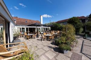an outdoor patio with tables and chairs and a building at Ferienwohnung Westerlicht - Apartment am Leuchtturm - De Torenhoeve in Nieuw-Haamstede