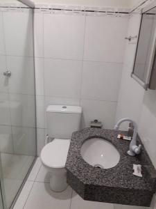 La salle de bains est pourvue de toilettes blanches et d'un lavabo. dans l'établissement Hotel Danubio, à Itabaiana