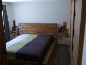 1 dormitorio con 1 cama con cabecero de madera en SZARVASKŐ NYARALÓ/ DEER ROCK COTTAGE en Esztergom