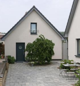 une maison blanche avec une porte noire et une terrasse dans l'établissement Ferienhaus Schleeff, à Elsfleth