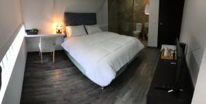 1 Schlafzimmer mit einem weißen Bett, einem Schreibtisch und einem Bett von sidx sidx sidx sidx sidx in der Unterkunft Hotel OrangeTrip in Bogotá