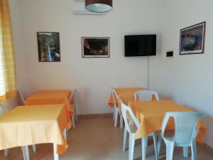 a restaurant with orange tables and chairs and a flat screen tv at Hotel Noto Marina Stella Marina - B&B in Noto Marina
