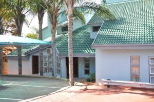a building with a tennis court and palm trees at Montana Boutique Guesthouse in Pretoria