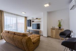 een woonkamer met een bruine bank en een televisie bij Pure Relax in Malinska