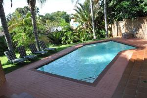 a swimming pool with two chairs and a brick patio at Montana Boutique Guesthouse in Pretoria