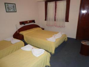 Habitación de hotel con 3 camas y toallas. en Hotel Shelter en Mar de Ajó