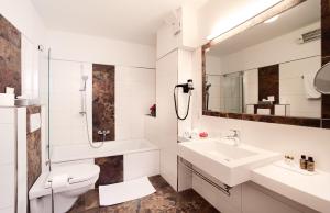 a bathroom with a sink and a toilet and a mirror at Hotel Seewinkel in Fuschl am See +37 photos