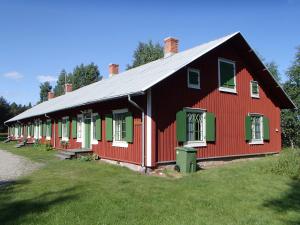 a red barn with green shutters on a field at Statarlängan Hörnefors in Hörnefors