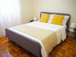 a bedroom with a large bed with yellow pillows at Viana Lovers in Viana do Castelo