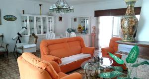 Sala de estar con 2 sillas de color naranja y mesa en La Maison dos Prazeres, en Portimão