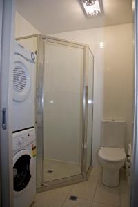 a bathroom with a shower and a toilet and a washing machine at Apartments on Chapman in Melbourne