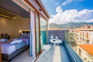 a bedroom with a bed and a table on a balcony at Ossuna Bay Hotel Boutique in Cefalù