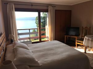 a bedroom with a large bed and a large window at Las Juntas Ecolodge in Puyehue