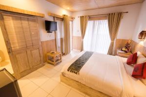 a bedroom with a large white bed and a television at Kubu Betel Home Stay in Canggu