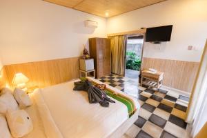 a hotel room with a bed and a television at Kubu Betel Home Stay in Canggu