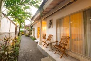 une terrasse couverte avec des chaises et des arbres dans l'établissement Kubu Betel Home Stay, à Canggu