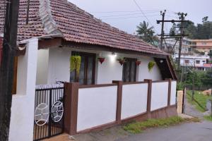 una pequeña casa blanca con una valla de madera en Agasthya Homestay - With Kitchenette, en Madikeri