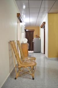 Duas cadeiras de madeira num corredor com um frigorífico em Agasthya Homestay - With Kitchenette em Madikeri