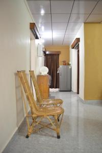 Dos sillas de madera en un pasillo con un refrigerador. en Agasthya Homestay - With Kitchenette, en Madikeri