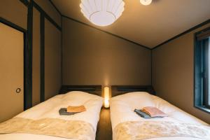 two beds in a small room with a light at Miro Sanjo Umemiyacho Tei in Kyoto