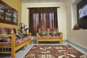 uma sala de estar com duas cadeiras e uma janela em Agasthya Homestay - With Kitchenette em Madikeri