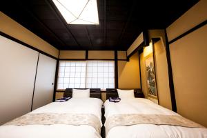 two beds in a room with a window at Miro Kyoto Shichjo Hanabatakecho Tei in Kyoto