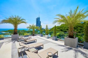 a patio with tables and chairs and palm trees at The Point by Tech in Pattaya South