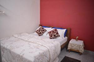 Un dormitorio con una cama y una pared roja. en Agasthya Homestay - With Kitchenette, en Madikeri