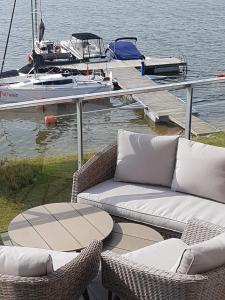 リジェボにあるApartament z widokiem na jezioroの船上の桟橋に位置する籐の椅子2脚とテーブル