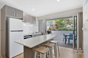 a kitchen with a white refrigerator and some chairs at Nobby Beach Holiday Village in Gold Coast