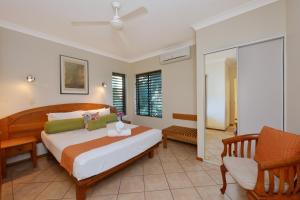 a bedroom with a bed and a chair at Seascape Holidays - Hibiscus in Port Douglas