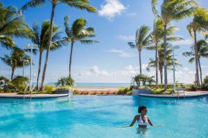 une femme dans une piscine d'un complexe avec des palmiers dans l'établissement Hyatt Vacation Club at Windward Pointe, à Key West